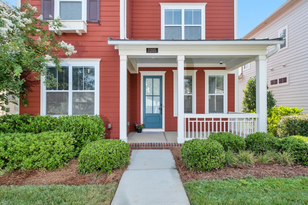 photo of a timeless exterior design in a farmhouse style with matching door and window styles with red siding and a blue door