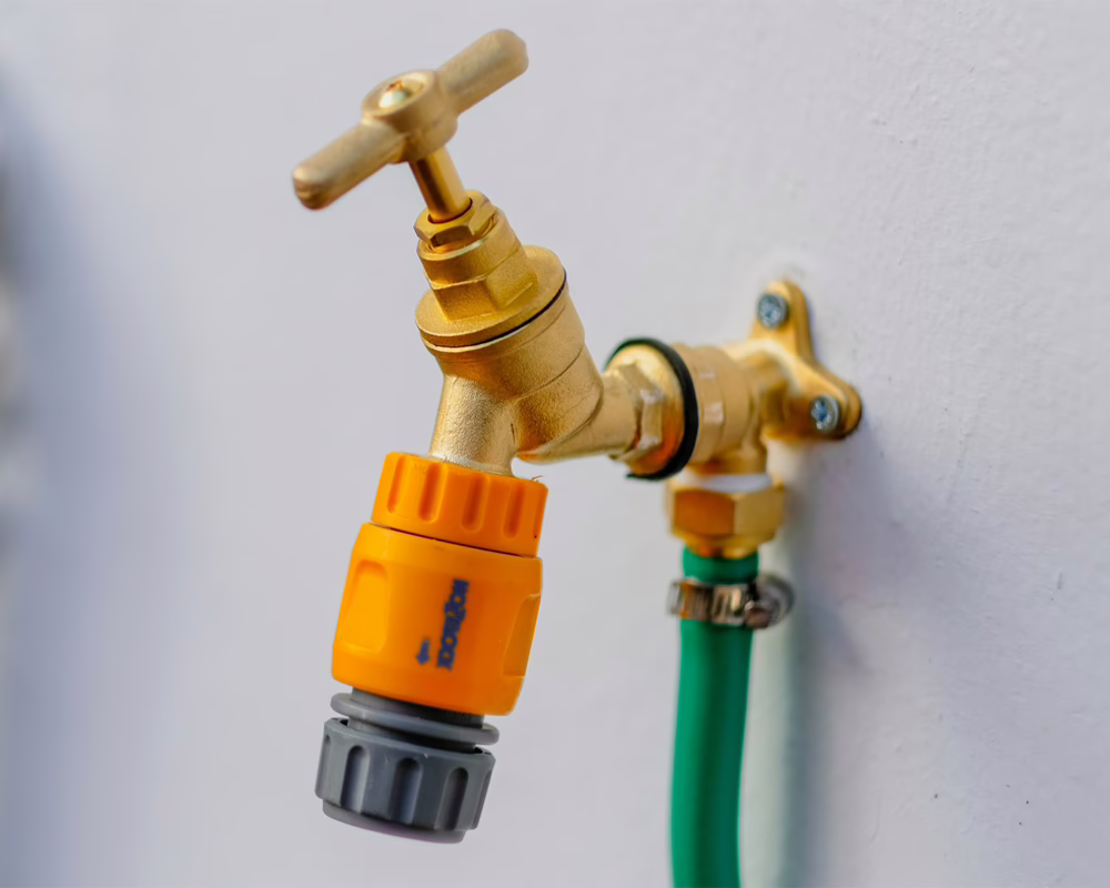 a brass water spigot on an exterior wall that has been painted white
